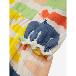 Bobo Choses - off white muslin dress with all over abstract carnival print in yellow, red, green and blue