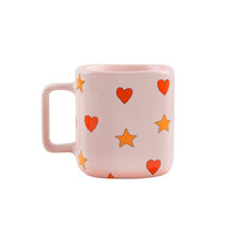 Load image into Gallery viewer, Tinycottons - pale pink ceramic mug with all over red heart and yellow star design
